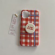 a red and white plaid cell phone case with a button that says lazing & hot on it