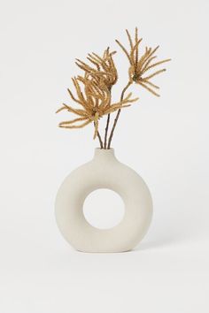 a white vase with some plants in it