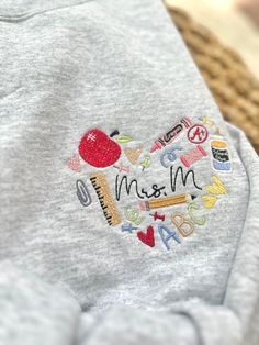 a child's sweatshirt with the word ms and m embroidered on it, in front of a wicker basket