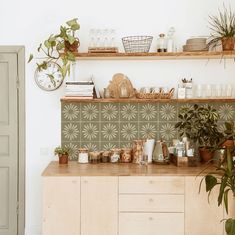 a kitchen counter with pots and plants on it, next to a wall mounted clock