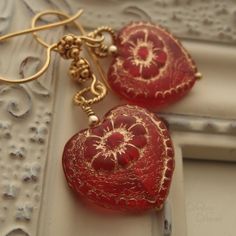 "Beautiful red glass hearts, etched in gold, hang from delicate, twisted wire loops and decorative earwires of vermeil. A lovely gift for yourself or somebody else on Valentine's Day. Length from bottom loop of earwire: 1\"(25mm) Diameter of heart: 3/4\"(20mm) All Debra Dane jewelry arrives in a pretty box suitable for gifting. These earrings are also available with non-pierced gold plated clips. They will have a gold ball instead of the ornate piece that is on the pierced earwires." Cheap Vintage Earrings For Valentine's Day, Red Heart Earrings For Wedding, Vintage Red Heart Earrings As Gift, Vintage Red Heart Earrings For Gift, Red Vintage Heart Earrings For Gift, Red Vintage Heart Earrings For Gifting, Red Heart Beads Earrings For Gift, Red Dangle Heart Earrings For Wedding, Elegant Red Heart Beads Earrings