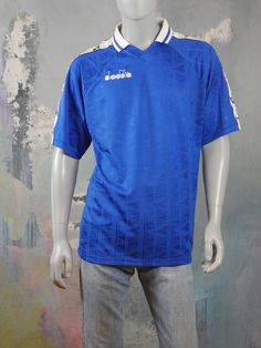 This 1990s Diadora short-sleeve football jersey is a beautiful combination of satin-sheen blue with a white collar with blue stripe. A wide band with black Diadora logo symbols runs across the shoulder line and down the side of each short sleeve. The brand name is embroidered in white on the right chest, and the brand symbol is etched throughout the fabric. Brand label: Diadora Size: XL (best fit = 42 to 44 US/UK) Material: Polyester Condition: Near Mint, Never Worn ---MEASUREMENTS--- Chest = 46 Football Season Short Sleeve Sportswear Jersey, Football Season Short Sleeve Sport Jersey, Short Sleeve Football Season Sportswear Jersey, Sportswear Football Season Short Sleeve Jersey, Leather Waistcoat, Retro Sportswear, Best Blazer, Long Overcoat, Blue Football