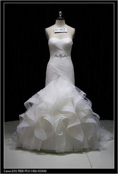 a white wedding dress on display in front of a black background