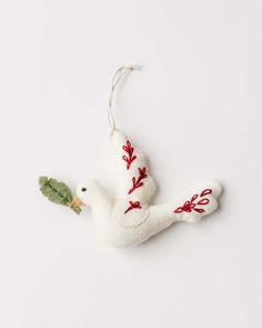 a white bird ornament with red and green leaves on it's body