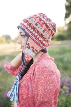 a woman wearing a red and white hat in a field with purple wildflowers