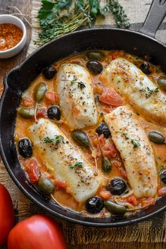 some fish in a red sauce with olives and tomatoes