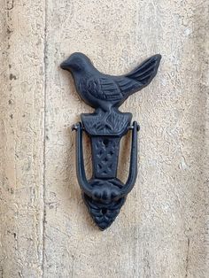 a black bird is perched on the handle of a door knocker that has a hook attached to it