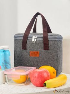 a lunch bag sitting on top of a table next to fruit and water bottles in front of it