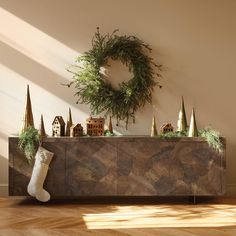 a christmas wreath and decorations on top of a wooden cabinet in front of a wall