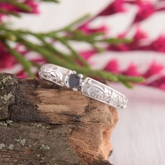 two silver rings sitting on top of a piece of wood with flowers in the background