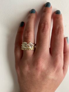 a woman's hand wearing a gold ring with two stones on the middle and one stone in the middle