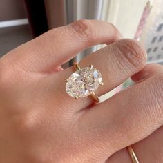 a woman's hand holding an engagement ring with two diamonds on it and the middle finger