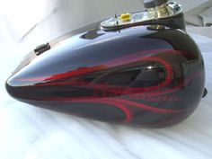 a close up of a motorcycle helmet on a white sheet with red and black flames