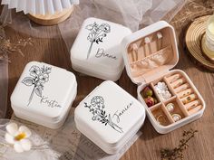 three white boxes with flowers and writing on them sitting on top of a wooden table