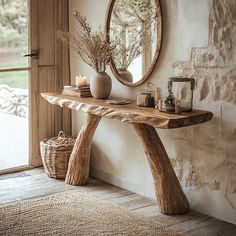 a wooden table sitting in front of a window next to a mirror and vase on top of it