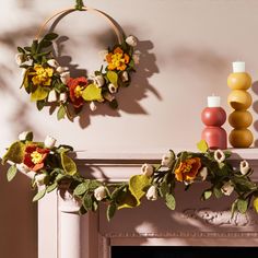 two wreaths with flowers are hanging on the fireplace mantel