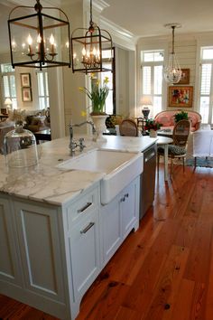 a large kitchen with an island in the middle and lots of lights hanging from the ceiling