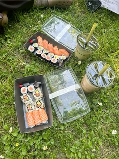 three trays of sushi are sitting on the grass next to an iced drink