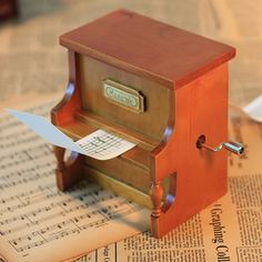 a small wooden box sitting on top of a newspaper with a piece of paper sticking out of it