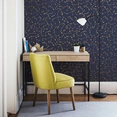 a yellow chair sitting in front of a desk with a lamp on top of it