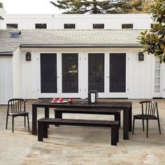 an outdoor table and chairs are set up in front of a white house