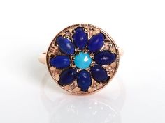 Round Flower Rose Gold Ring. Inspired by mandala geometric forms and organic floral pattern this ring has a  Center turquoise stone surrounded by beautiful beads of lapis lazuli, all set in our beautiful custom 14k vintage rose gold alloy. Details and Measurements:► 14 Karat Rose Gold► Central Turquoise 4 mm► 8 Lapis Lazuli 4x6 mm► Size 8 (Select your size)► Total Weight 5.6 grAll items are Handmade, I pay a lot of attention to every piece.All of my items are hand crafted in Kisufim's Designer j Bohemian Flower Ring With Gemstone, Bohemian Flower Ring For Jewelry Making, Bohemian Gemstone Flower Ring As Gift, Handmade Blue Flower Ring, Mandala Blue, December Birthstone Ring, Vintage Rose Gold, Round Flower, Beaded Jewels