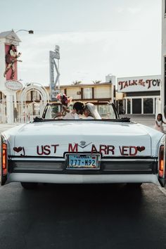 a bride and groom kissing in the back of a white convertible car at a motel