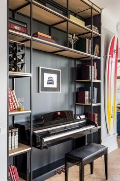 a room with a piano, bookshelves and a surfboard