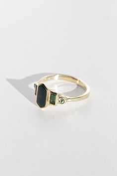 a gold ring with two green stones on the front and one stone in the back