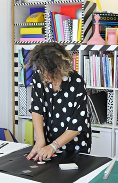 a woman is typing on her laptop in front of a bookcase