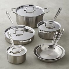 an assortment of pots and pans with lids on a gray tableclothed surface