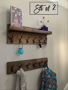 two wooden shelfs with hooks on them are hanging from the wall next to a coat rack