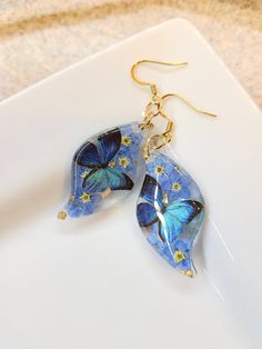 How darling are these Real Flower earrings! Perfect for yourself or for your loved ones.  The Dangles are made with real pressed forget me not flowers and Cerulean Butterflies with a hint of gold flakes.  All Jewelry findings are Nickel and Lead Free. The petals and ferns have been carefully preserved to retain their color and would make a great gift for your loved ones. This piece was made with real flowers and hence it is important to preserve the jewelry in the box provided safely away from direct sunlight.  You can see more of my Handmade Items here:  https://www.etsy.com/shop/Thecraftiechristie Whimsical Teardrop Earrings For Pierced Ears, Whimsical Teardrop Jewelry For Pierced Ears, Artistic Dangle Flower Earrings For Gifts, Artistic Dangle Flower Earrings As Gift, Artistic Flower Shaped Ear Wire Jewelry, Bohemian Handmade Earrings, Gift For Her, Handmade Nature-inspired Jewelry For Mother's Day, Handmade Bohemian Earrings As Gift For Her, Bohemian Handmade Earrings As Gift For Her