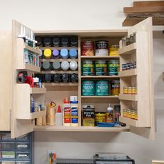 an open cabinet in a kitchen filled with paint and other items