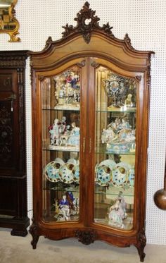 an antique china cabinet with glass doors and ornate carvings on the front, along with other antiques