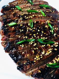 the steak is covered with sesame seeds and garnished with green leaves on top