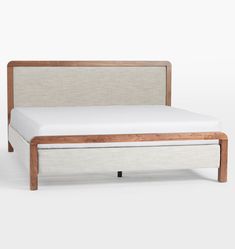 an upholstered bed frame with white linen and wood slats on the headboard