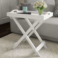 a white table with flowers on it in front of a couch