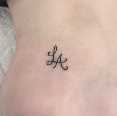 a small tattoo on the back of a woman's lower leg, with an initial