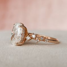 a close up of a ring with an oval shaped diamond on top and small round diamonds around the band