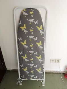 an ironing board with yellow and gray butterflies on it next to a white wall