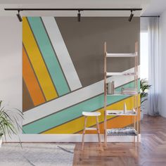 an abstract painting in yellow, green, orange and white on a wall next to a plant