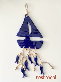 a blue sailboat ornament hanging from a string with white beads on it