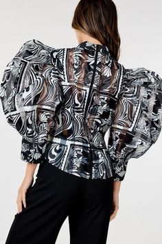 The printed design adds personality and flair making it perfect for both casual and dressed up occasions. The sheer texture adds a touch of allure while the back zipper adds a modern twist. Whether worn with a skirt or pants for a formal event this top is a stylish addition to your wardrobe. - Print - Collarless - Long sleeve I Puffed Chic Long Sleeve Blouse With Abstract Print, Black Office Top With Sheer Sleeves, Trendy Fitted Blouse With Sheer Sleeves, Glamorous Fitted Office Tops, Chic Patterned Tops With Abstract Print, Black Sheer Blouse With Puff Sleeves, Sheer Puff Sleeve Chic Blouse, Fitted Abstract Print Top For Party, Chic Blouse With Sheer Sleeves For Office