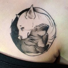 a black and white photo of a cat in a circle tattoo on the back of a man's shoulder