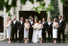 a group of people standing next to each other in front of a building with ivy growing on it