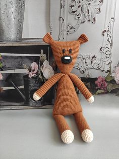 a crocheted brown teddy bear sitting next to a framed photograph and flower pot