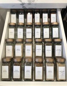 many jars with labels on them are stacked up in a shelf next to each other