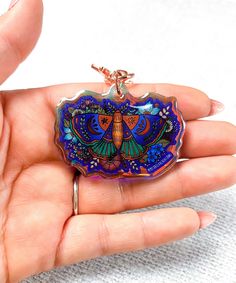 a hand holding a colorful butterfly shaped keychain