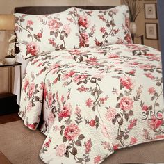 a bed covered in a white and pink flowered bedspread